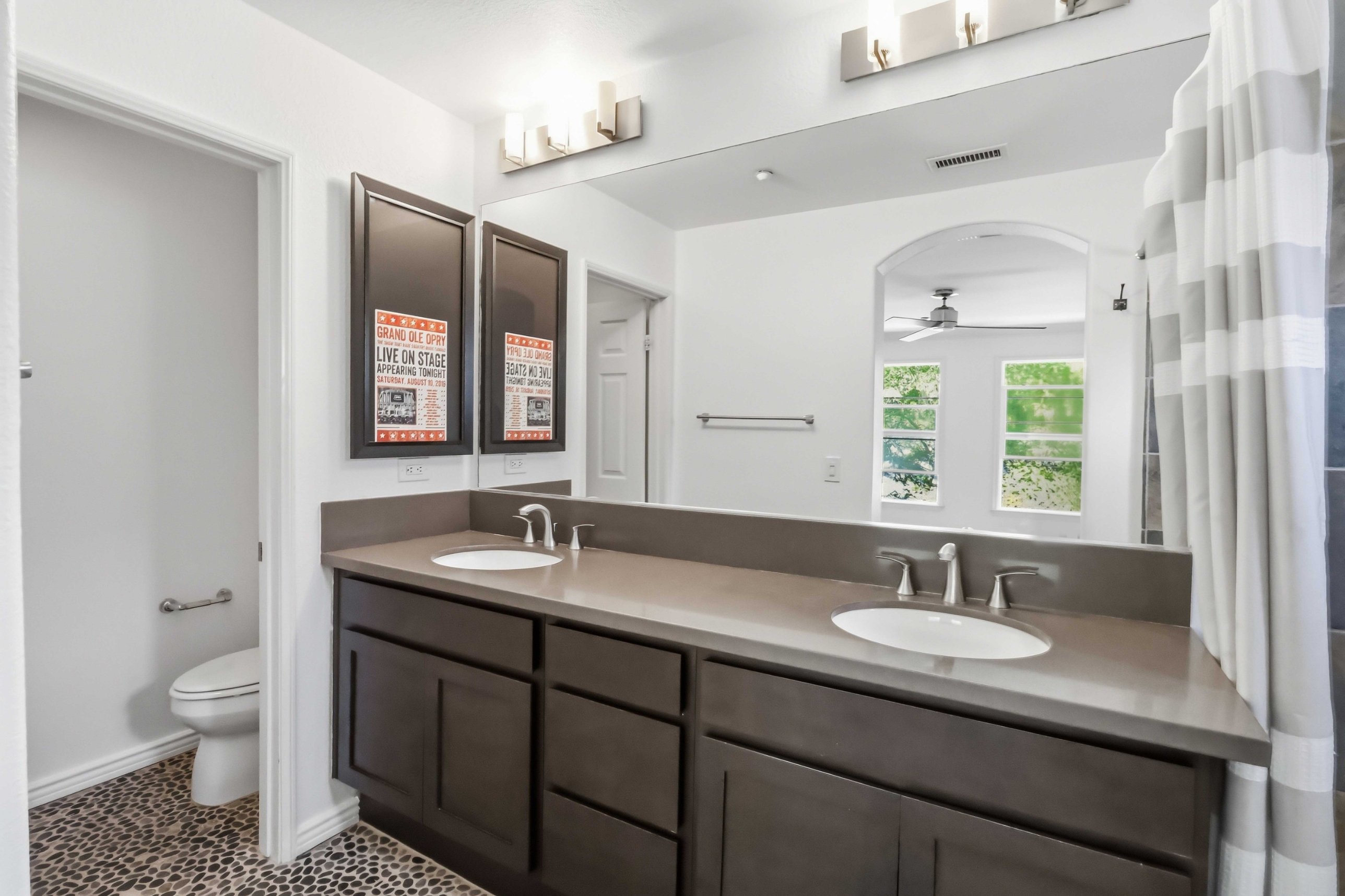 Primary bedroom with ceiling fan, large windows, and mirrored closet entry.